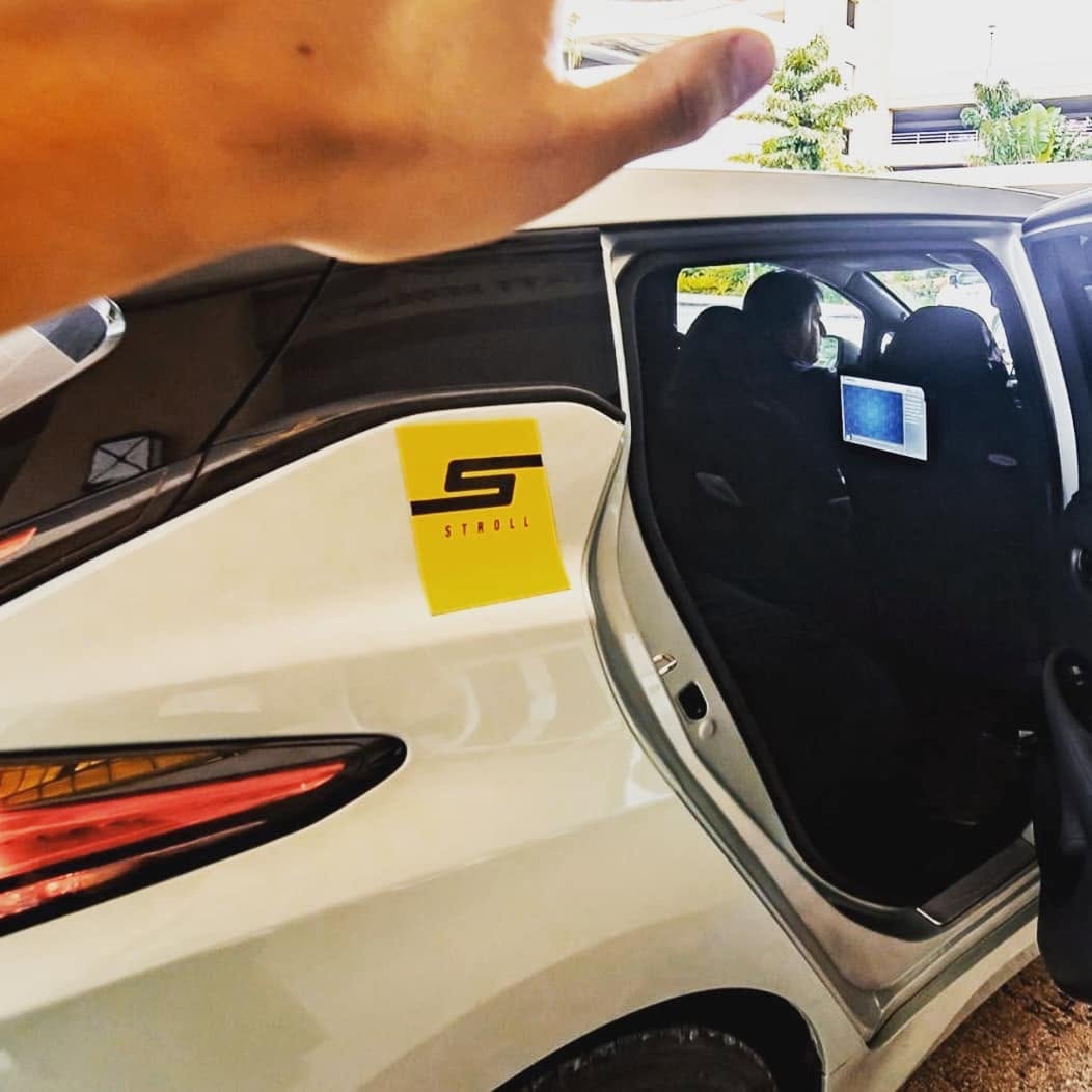Archival photo of a Stroll Guam branded vehicle with an AdResst headrest display visible in the back seat, 2019